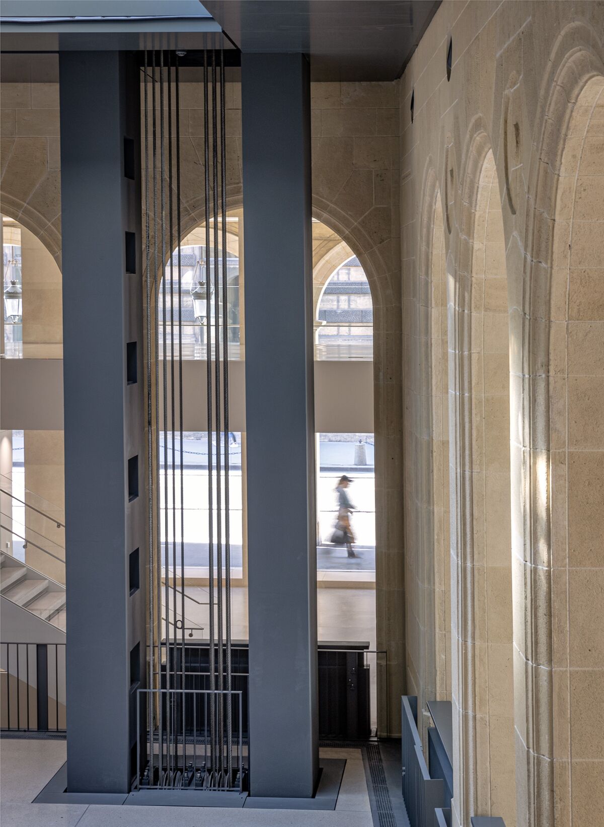 Detail view of lift cables alongside 19th-century stone arcades at Fondation Cartier